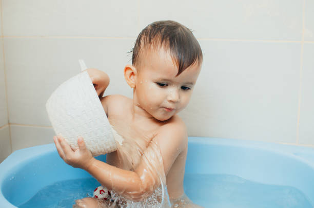 Happy boy taking a bath, pour water with a white bucket
