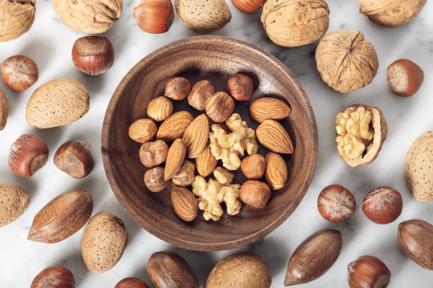 Nuts Mixed in a wooden plate Nuts Mixed in a wooden plate. Assortment, Walnuts, Pecan, Almonds, Hazelnuts. Healthy appetizer almond tree photos stock pictures, royalty-free photos & images