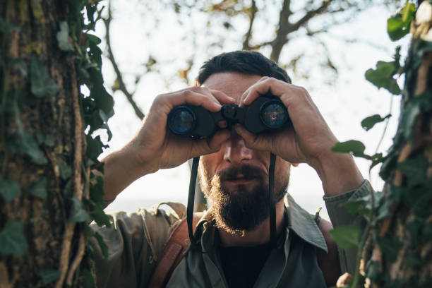 istock Man in the forest looks through binoculars 1133183642