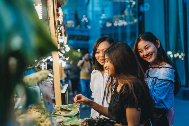 Three friends buying street food at the night market in the city Three friends buying street food at the night market in the city cambodian ethnicity stock pictures, royalty-free photos & images