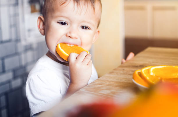 istock The child in the kitchen eating an orange 1133185436