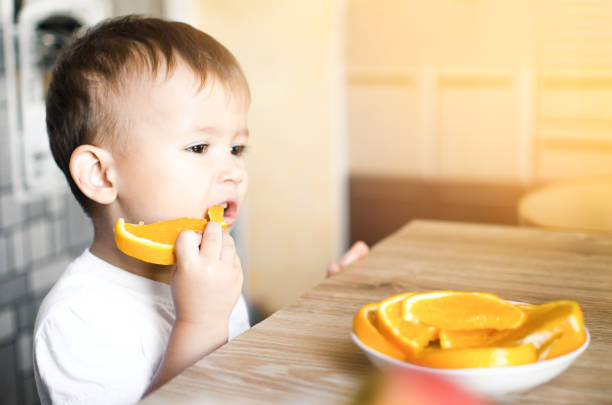 istock The child in the kitchen eating an orange 1133185442