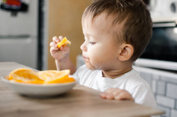 istock The child in the kitchen eating an orange 1133186437