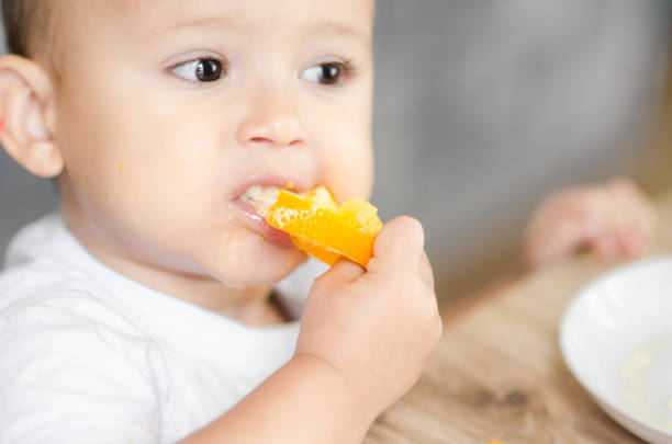 istock The child in the kitchen eating an orange 1133187409