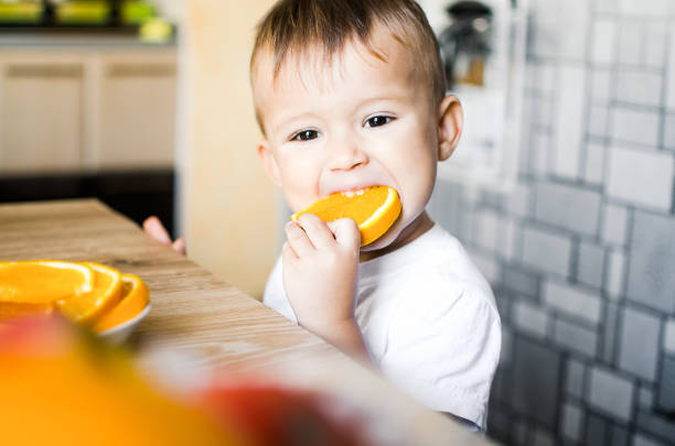 istock The child in the kitchen eating an orange 1133188907