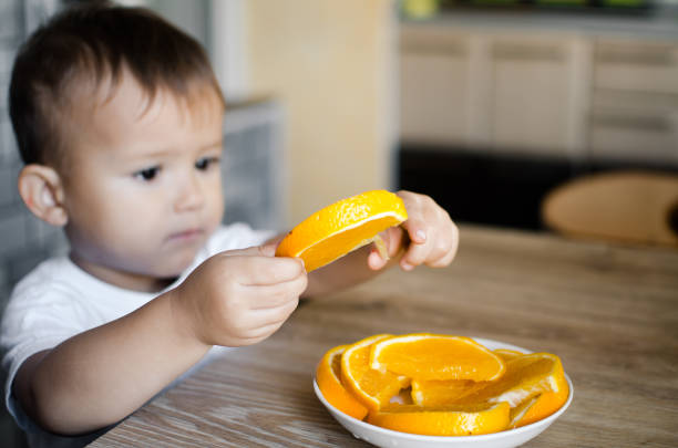 istock a child takes slice of orange 1133189055