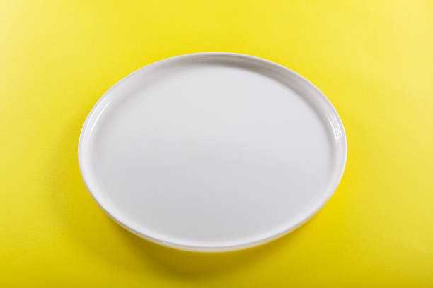 istock A white plate on the yellow background 1133189064