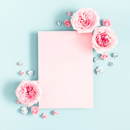 Flowers composition. Frame made by roses, branches and petals on pink background. Flat lay top view with copy space in the center