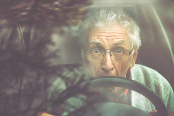 istock Old gentleman drives car and makes a funny face 1133192060