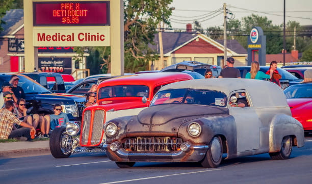 1952 Chevrolet sedan delivery & 1933 Pontiac streetrod Moncton, New Brunswick,  Canada -  July 12, 2014.  On Saturday evening, 1952 Chevy sedan delivery & 1933 Pontiac street rod cruise on Mountain Rd, during 2014 Atlantic Nationals Automotive  Extravaganza. People sit & stand on the sidewalk to watch the classic cars cruise by. cruising hot rods stock pictures, royalty-free photos & images