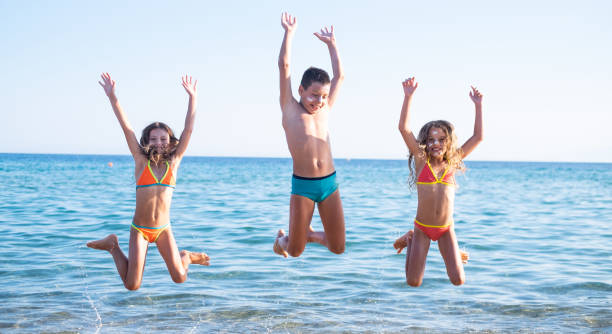 istock Three cute kids jumping at the beach 1133193753