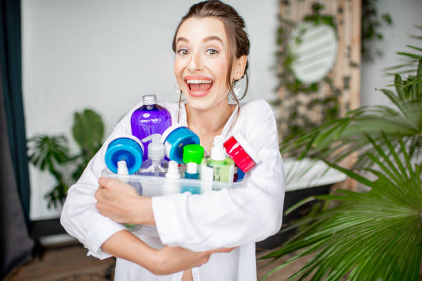 woman with colorful bottles for self-care in the bathroom - clear sky human skin women smiling imagens e fotografias de stock