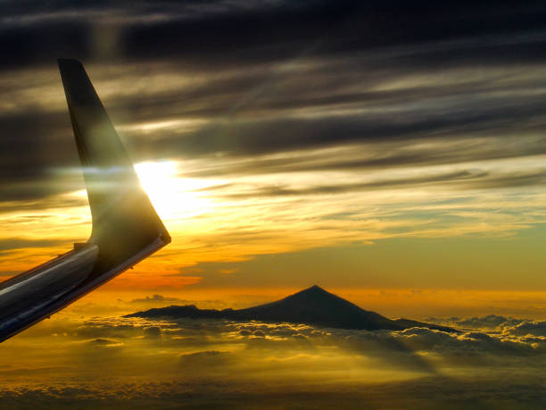 Pico del Teide, the highest mountain of Spain on the Canary Island of Tenerife, rises through the clouds at sunset, photographed from above from an airplane
