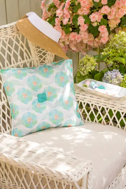 Fabric pillow, needle, thread and buttons sewing notions on chair in garden. Spring and summer home decorating crafts projects.
