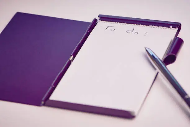 empty to do list, handwritten, on a white pad in a violet metal box, pen beside, focus on the word do