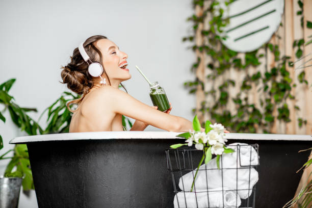 mulher nova que relaxa na banheira - bathtub women relaxation bathroom - fotografias e filmes do acervo