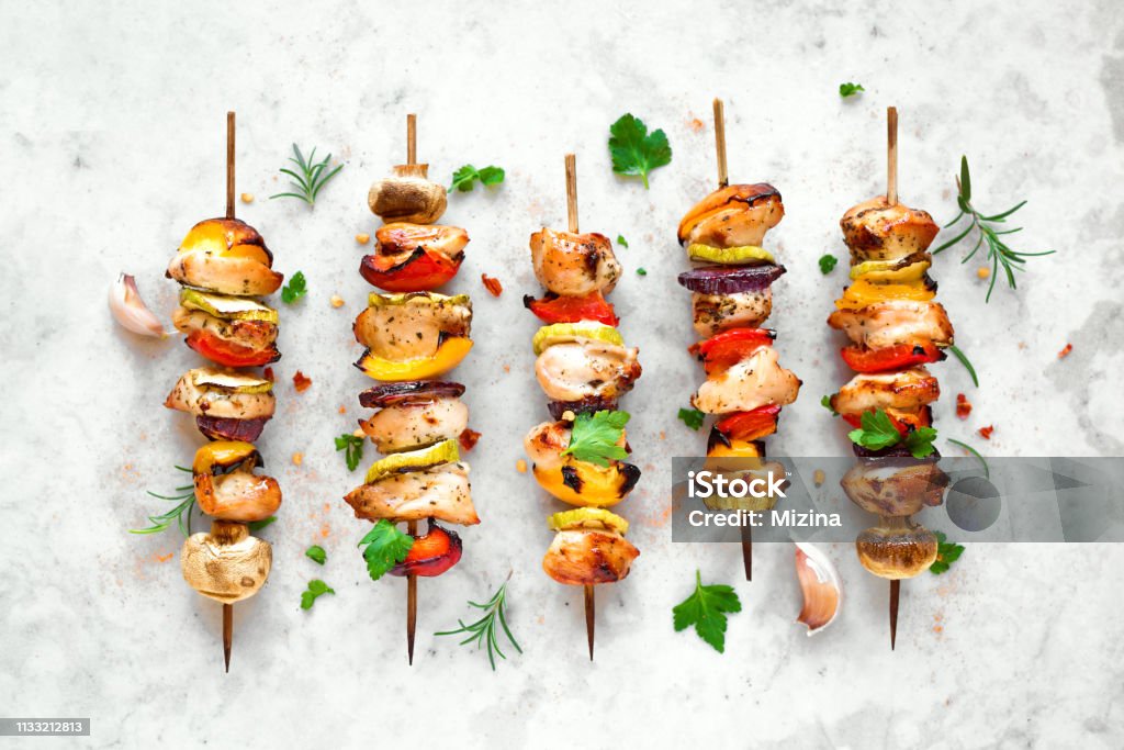 Grilled vegetable and chicken skewers Grilled vegetable and chicken skewers with  bell peppers, zucchini, onion and mushrooms on white marble background, top view. Meat and vegetables kebabs on skewers. Kebab Stock Photo