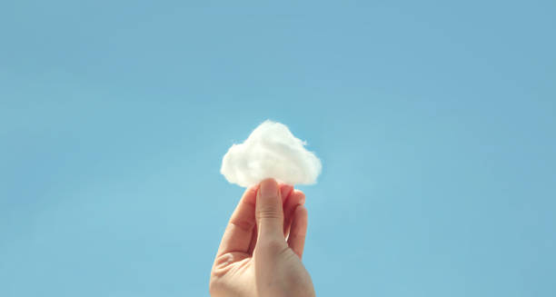 istock Hand holding cotton wool with cloud on sky background. The development of the imagination 1133217241