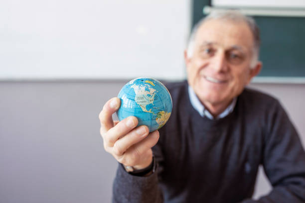 Senior teacher holding in hand globe stock photo