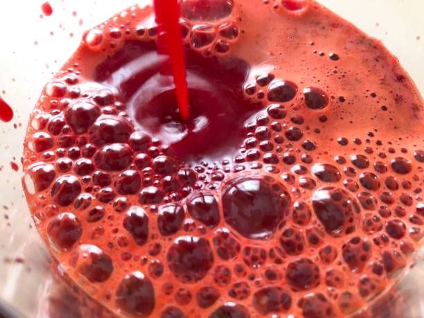 Fresh Beet Carrot Juice Bright red glass of freshly juiced organic beet, carrot, apple, and red pepper on a neutral table carrot juice stock pictures, royalty-free photos & images