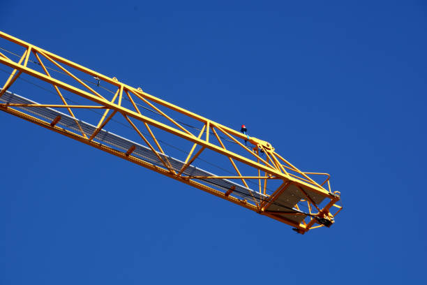 istock yellow construction tower crane arm with red warning light in front of clear blue sky 1133221252