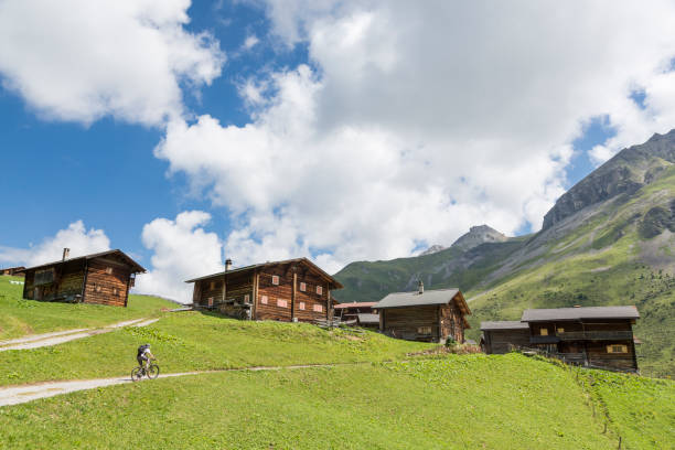 mountainbiker que aproxima uma vila alpina no vale de fondei, davos. - davos switzerland summer mountain - fotografias e filmes do acervo