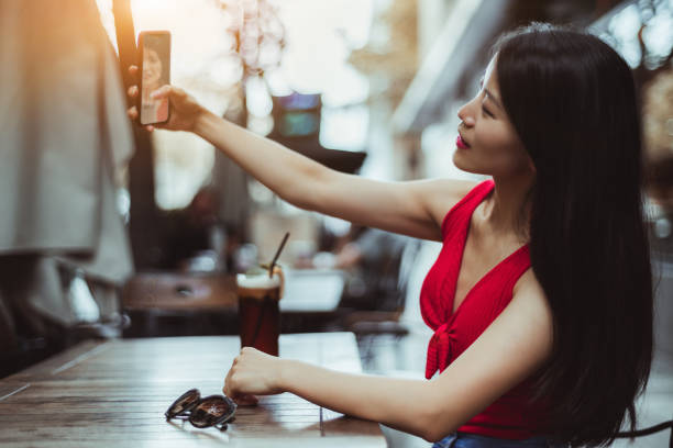 fille asiatique faisant le selfie sur le téléphone portable - red text messaging cafe teenage girls photos et images de collection