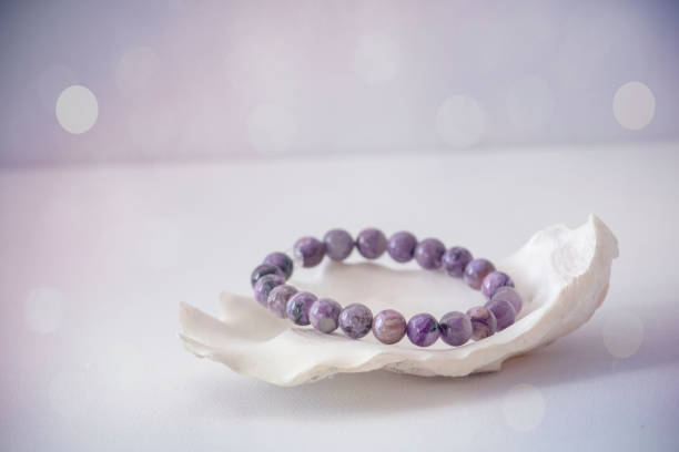 Amethyst Bracelet An amethyst bracelet in a seashell with a white and purple bokeh background. chakra recovery energy gem stock pictures, royalty-free photos & images