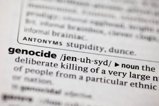 Close up to the dictionary definitions of the word Genocide