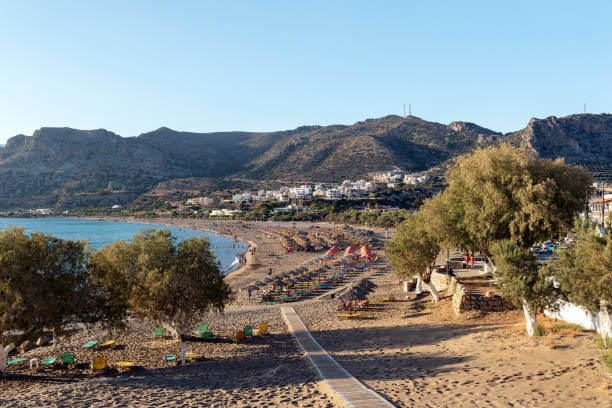 wooden pathway to sandy beach at palaiochora town at southern part of crete island, greece - sky sea town looking at view imagens e fotografias de stock