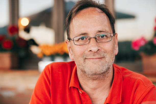 Outdoor portrait of 50 year old man wearing red polo shirt and eyeglasses stock photo