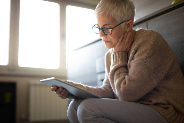 Worried senior woman reading an e-mail on tablet Serious senior woman using tablet computer indoors seems concerned introspection photos stock pictures, royalty-free photos & images