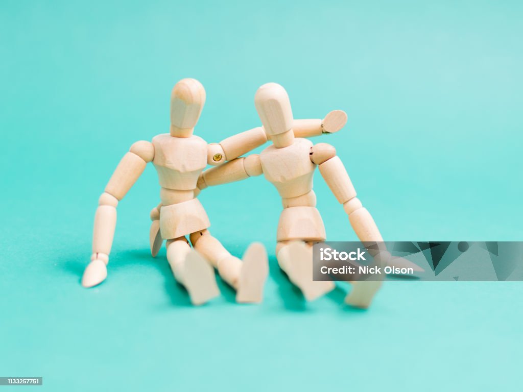 Mannequin friends Friendly wooden mannequins hug on light blue background Side By Side Stock Photo