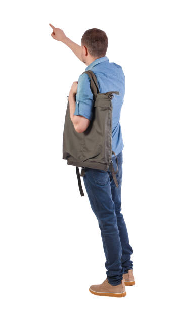istock Back view of a man with a green backpack pointing forward. 1133258167