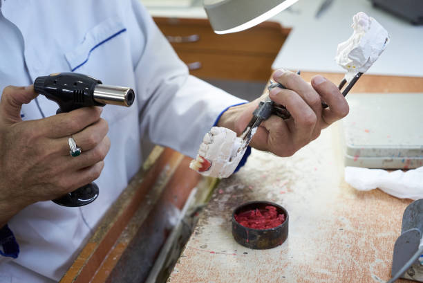 istock Dentist hands holds prostheses on a plaster jaw in the lab 1133258926