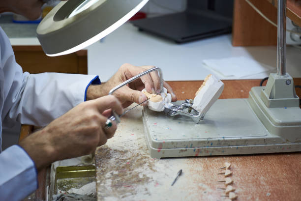 istock Dentist hands holds prostheses on a plaster jaw in the lab 1133258931
