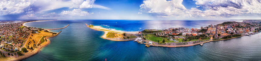 Delta of Hunter river entering Pacific ocean near Newcastle city and port on a sunny summer day in wide aerial panorama of Newcastle waterfront and NObbys head against Stockton beach.