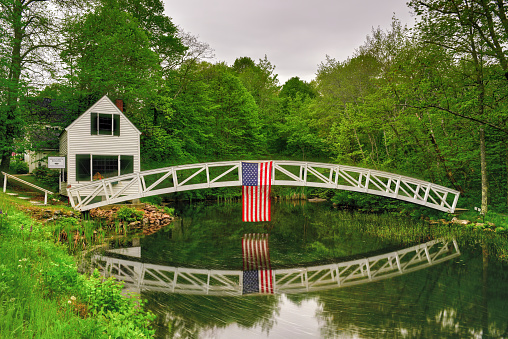 Footbridge in Somesville, Mount Desert Island in Maine with the USA Flag reflecting in the pond.