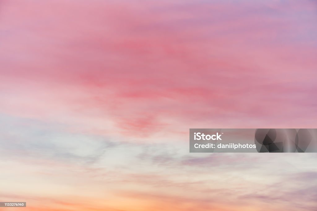 Sunset sky with pink yellow light clouds. Colorful smooth blue sky gradient. Natural background of sunrise. Amazing heaven at morning. Slightly cloudy evening atmosphere. Wonderful weather on dawn. Atmospheric Mood Stock Photo