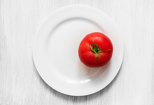 Red tomato on a white plate