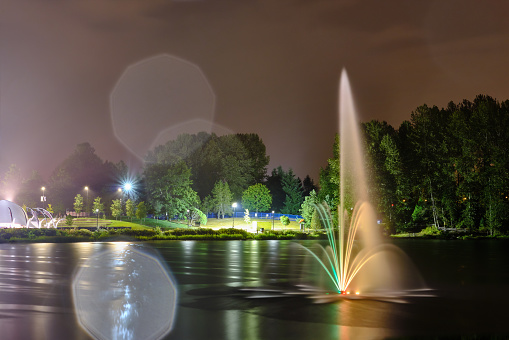 Lafarge lake public park fountain in Coquitlam city, Great Vancouver, BC, Canada. Night view, multi color reflection