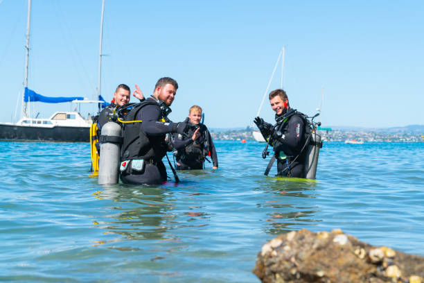 Divers entering water at Pilot Bay wharf for annual beach clean giving the divers signal for OK, March 2019 Tauranga New Zealand