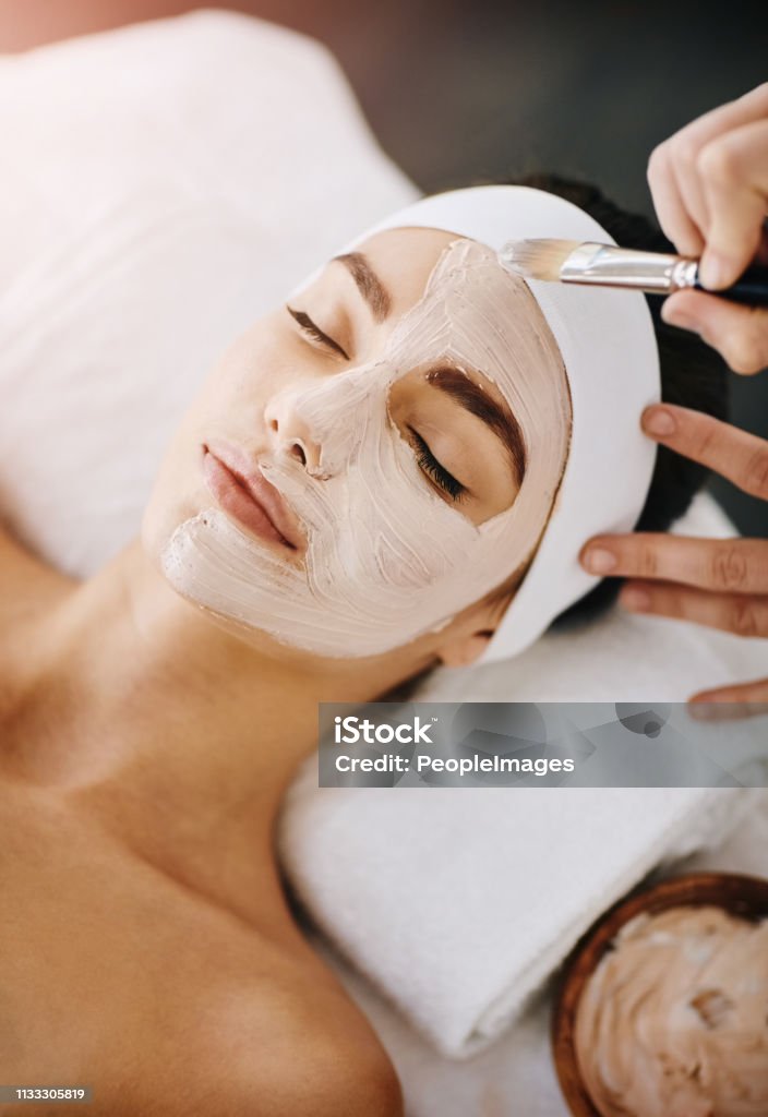 Turning dull skin into a thing of the past Shot of an attractive young woman getting a facial at a beauty spa Facial Mask - Beauty Product Stock Photo