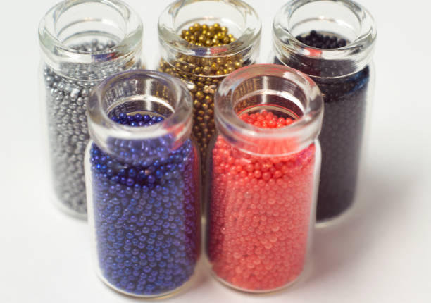 istock Multicolored beads in glass jars. Beads are poured on a white background. Plastic multi-colored polymers. Plastic pillets. 1133315346