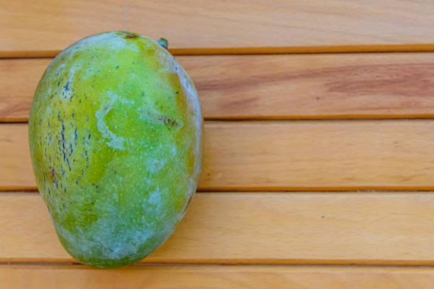 istock Green mango fruit on a wooden table. Top view 1133316500