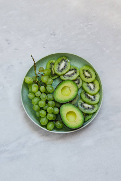 istock grapes, avocado and kiwi fruit in green rustic plate on marble texture background with copy space 1133318717