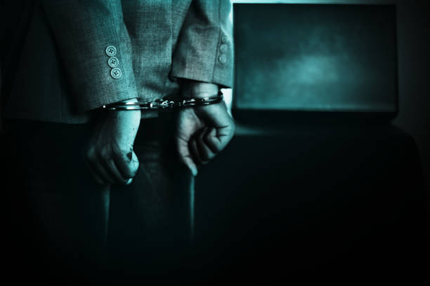 Close-up photo of a well-dressed man's hands in handcuffs.