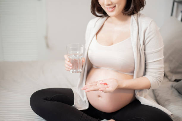 Close up pregnant woman eating vitamin pills stock photo
