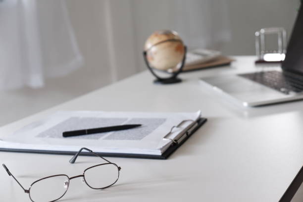 istock Office desk table with glasses, pen, pencil, laptop and world map. 1133326656