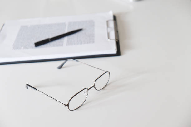 istock glasses with document and pen on table in office, class room. 1133326670